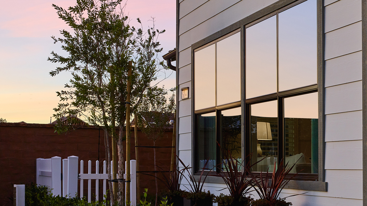 Home exterior with sunset reflecting in AMBLA INC single hung windows with simulated divided lites.